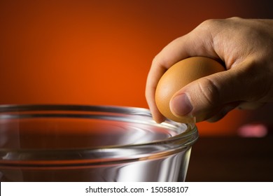 Man's Hand Cracking And Pouring An Egg Into A Bowl.