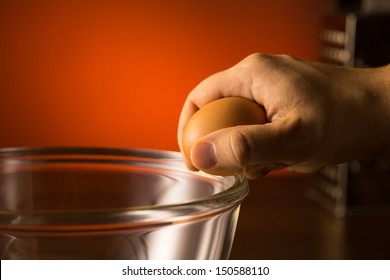 Man's Hand Cracking And Pouring An Egg Into A Bowl.