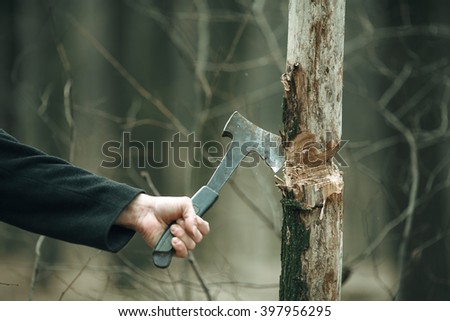 Man's hand cutting tree with an axe.