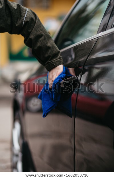 Man\'s\
hand disinfecting door handle of brown car by blue disinfectant\
wipe. Prevent the virus and bacterias, Prevent covid19, corona\
virus, Alcohol Sanitizer. Hygiene concept at\
home.