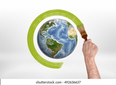 Man's hand encircles globe with a brush with green paint. Protection of the planet. Save planet. Environment and ecology.