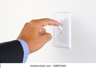 Man's hand with finger on light switch, about to turn off the lights. Closeup of hand and switch only. Horizontal format.