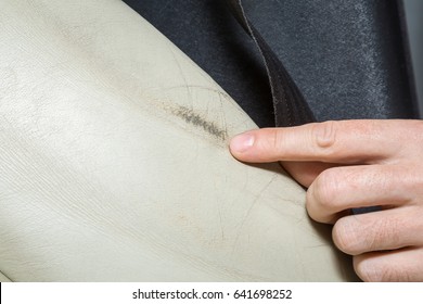 Man's Hand Finger Pointing To Car Interior's Damaged Leather Seat.