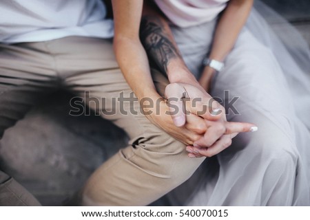 man's hand gently holds a female hand