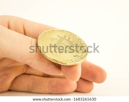 a man's hand is going to flip a gold coin bitcoin