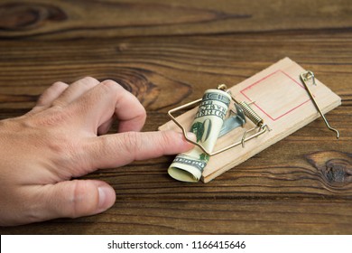 A Man's Hand Got Caught In A Mousetrap With Bait Money Dollar Bills. Concept Business Risk, Pimat The Attacker, Bribe.