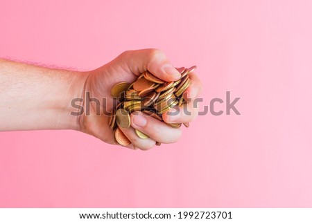 man's hand grabbing a pile of euro cent coins. changeover concept. greed