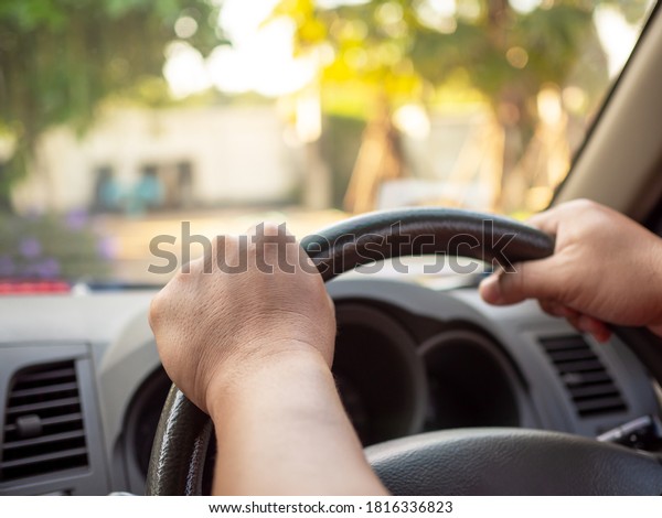 A man\'s hand held the steering\
wheel of a car to steer while the car was moving away. Concept and\
direction of business operations according to the\
plan.