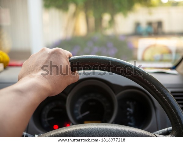 A man\'s hand held the steering\
wheel of a car to steer while the car was moving away. Concept and\
direction of business operations according to the\
plan.