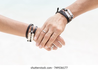 The man's hand hold the woman's hand. Close up hands with beautiful engagement rings. Style wedding. Fashionable couple. Hands with bracelets and blades.  - Shutterstock ID 749536177
