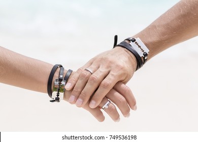 The man's hand hold the woman's hand. Close up hands with beautiful engagement rings. Style wedding. Fashionable couple. Hands with bracelets and blades.  - Shutterstock ID 749536198