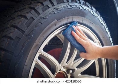 Man's hand holding a blue fabric cleaning car tires and wheels - Powered by Shutterstock