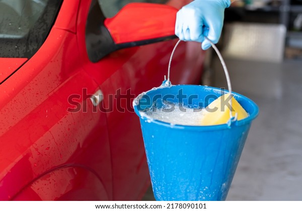 man\'s\
hand holding a bucket with soap to wash his\
car
