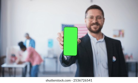 Man's hand holding cell phone with green screen. Blurred male showing green display. People filling out ballots while choosing new candidate for President in polling station. - Powered by Shutterstock