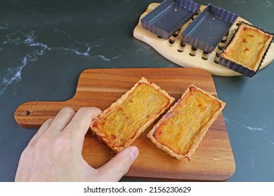 Man's Hand Holding a Fresh Baked Pumpkin Tartlet Placing on the Wooden Breadboard