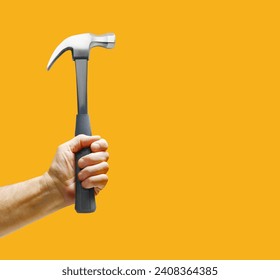 Man's hand holding hammer on orange yellow background. Copy space - Powered by Shutterstock