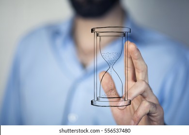 Man's hand holding hourglass sand  - Shutterstock ID 556537480