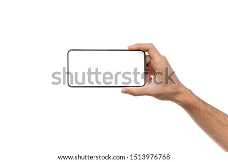 Man's hand holding modern smartphone with blank screen in horizontal orientation for mockup, copy space