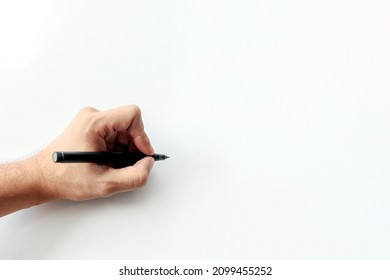 Man's Hand Holding A Pen Writing On White Background. Space For Text