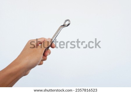 Man's hand is holding a ring spanner to tighten something.
