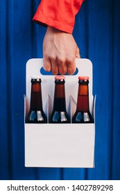 Man's Hand Holding A Six Pack Of Brown Beer Bottles 