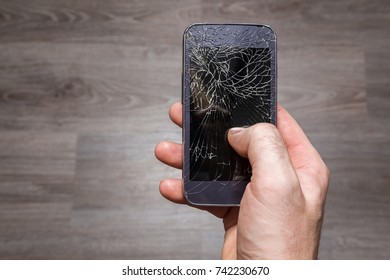 Man's Hand Holding Smart Phone With Damaged Screen. Problem Concept.