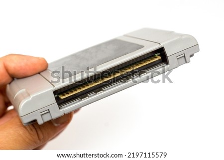 Man's hand holding of video game cartridge. Retro vintage 64 bit console game cartridge on a white background. Video game cartridge transparent background. 