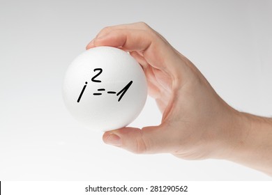 Man's Hand Holding White Blank Styrofoam Ball With Handwritten Imaginary Number Formula Against The White Background.