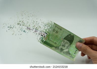 The man's hand holds a 10000 Korean won, which crushes and flutters in the wind. The concept of currency devaluation and economic crisis.collapse, stagnation ·economy.Spending and loans,covid 19.