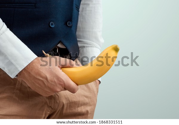 A man\'s hand holds a banana on the\
background of a fly, close-up. Potency concept, impotence, male\
strength, pills to improve potency. copy\
space