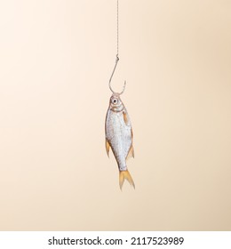 A man's hand holds the fish on a hook, on a yellow background. Concept, template.