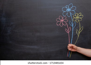 A man's hand holds flowers drawn on a chalkboard in his hand. - Powered by Shutterstock