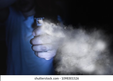 a man's hand holds a gas pepper spray in the dark, a black background. concept of safety and self-defense