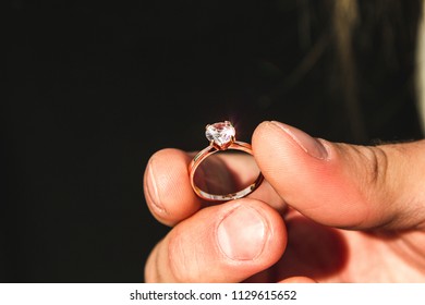 The Man's Hand Holds A Gold Ring With A Precious Stone