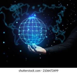 a man's hand holds a holographic globe on a dark blue background. Concept of globalization, world internet network, barrier-free