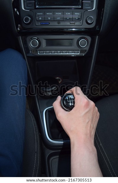 A man\'s hand holds the lever of the manual\
transmission in the car