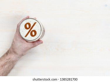 Man's Hand Holds A Mug Of Beer With Percent Sign On A Beer Foam. Top View. Space For Text