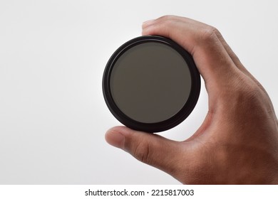 Man's Hand Holds A ND (neutral Density) Optical Filter Isolated On White Background