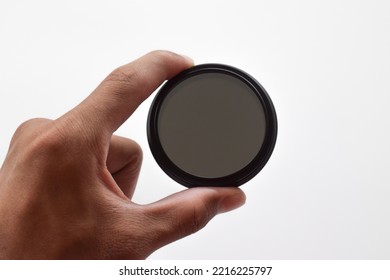 Man's Hand Holds A ND (neutral Density) Optical Filter Isolated On White Background