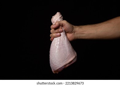 A Man's Hand Holds A Raw Turkey Leg On A Black Background. Fresh Turkey Meat