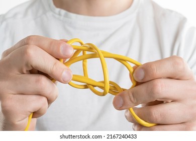 Man's hand holds tangled cords signifying solving a complicated problem - Shutterstock ID 2167240433