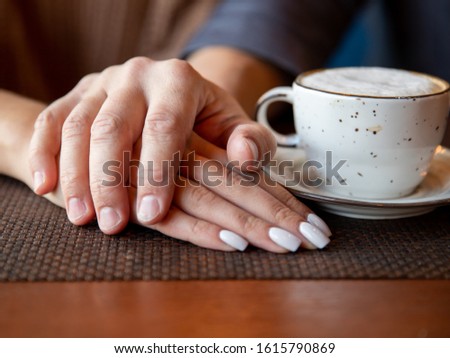 A man's hand holds a woman's, romance in a cafe. Valentine day