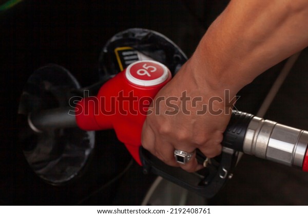 Man\'s hand is\
inserting a gas pump nozzle in a fuel tank, Car refueling on the\
petrol station, Oil and gas\
concept.