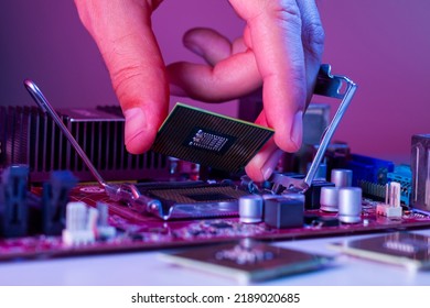 A man's hand inserts a processor into the motherboard socket.