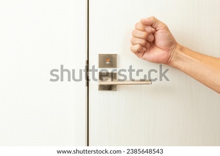 A man's hand knocking on the door.