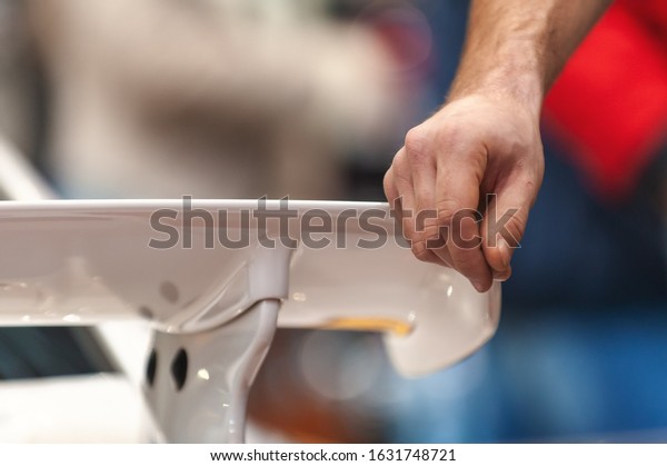 Man\'s hand\
leaning on a spoiler of a racing\
car.