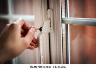 Man;s Hand Locking Or Opening A Double Glazing Window. Soft Focus And Shallow Depth Of Field, Vignette And Grain Added For Effect. 