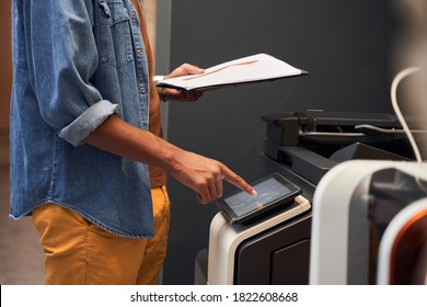 Man's hand making copies and working with printer. American man pressing the button at the printer machine