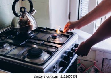 A man's hand with a match lights a gas burner or a gas stove in the kitchen.