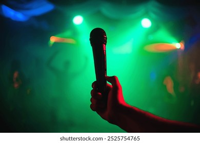 man's hand with a microphone on background of musical event in night club